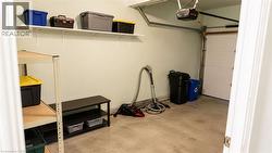 Single-car garage featuring a roll-up door, automatic opener, concrete flooring, and built-in wall shelving - 