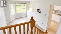 Open-concept living area with bay windows, light wood-finish flooring, and a neutral color palette - 