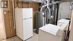 Utility area with a water heater, furnace, and a washer and dryer unit - 