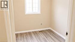 Room featuring light beige walls, wood-finish flooring, white baseboards, and a white-framed window with grids - 
