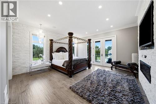 Spacious interior featuring wood-finish flooring, white stacked stone accent wall, recessed lighting, and crown molding - 7009 Wellington Rd 34, Puslinch, ON - Indoor With Fireplace