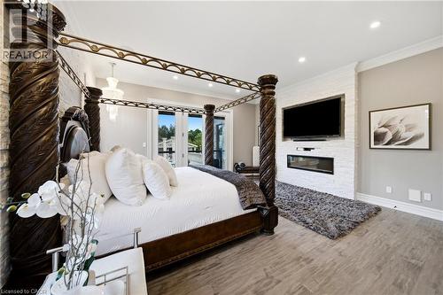 Spacious room featuring wood-finish flooring, a contemporary fireplace within a textured white accent wall, and recessed lighting - 7009 Wellington Rd 34, Puslinch, ON - Indoor Photo Showing Bedroom