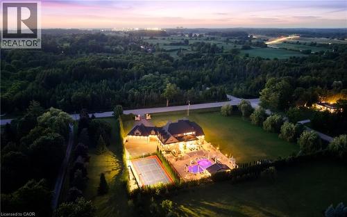 Expansive property featuring a large residence, tennis court, and illuminated pool area - 7009 Wellington Rd 34, Puslinch, ON - Outdoor With View
