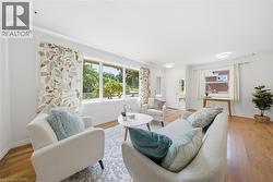 Bright living area featuring wood-finish flooring, white baseboards, and crown molding - 