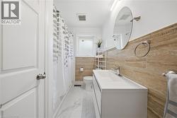 Contemporary bathroom featuring a white floating vanity with an integrated sink, brushed nickel fixtures, and a circular mirror - 