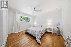 Bright room featuring wood-finish flooring, a contemporary ceiling fan with integrated lighting, a large window, and white trim throughout - 