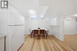 Open-concept kitchen area featuring light wood-finish flooring, white walls, recessed ceiling with contemporary flush mount lighting, and white cabinetry - 