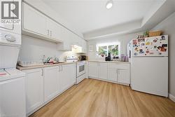 Kitchen featuring white cabinetry and wood-finish flooring - 