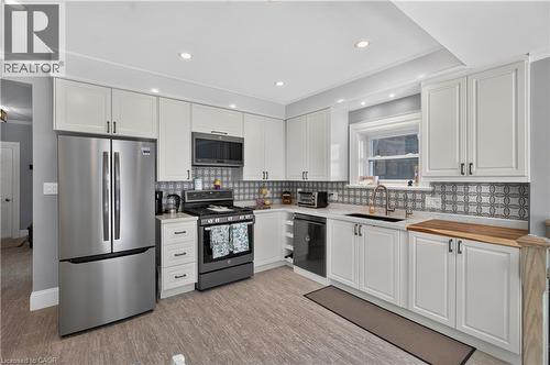 Modern kitchen featuring white shaker cabinetry, stainless steel appliances, patterned tile backsplash, and light wood-finish flooring - 9 Davidson Street, Cambridge, ON - Indoor Photo Showing Kitchen