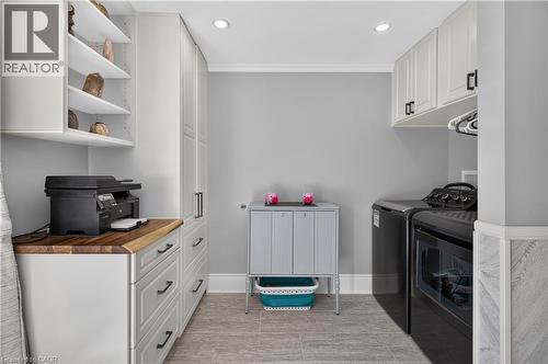Dedicated utility room featuring extensive white cabinetry with matte black hardware, a wood-finish countertop, recessed lighting, and tile flooring - 9 Davidson Street, Cambridge, ON - Indoor Photo Showing Laundry Room
