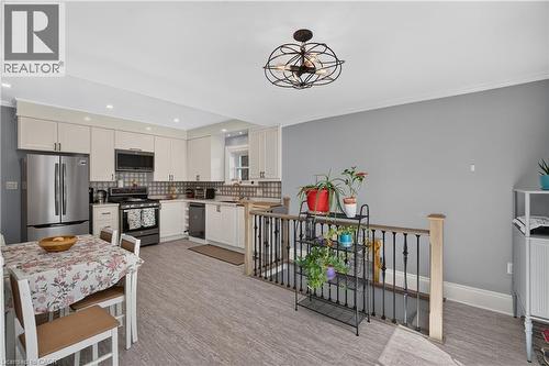 Open-concept kitchen and dining area featuring light-toned cabinetry, stainless steel appliances, a decorative backsplash, and wood-finish flooring - 9 Davidson Street, Cambridge, ON - Indoor Photo Showing Kitchen