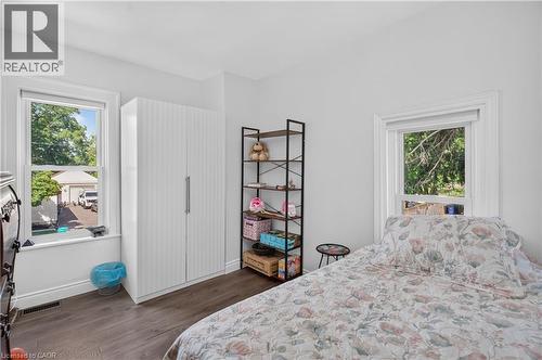 Bright room featuring two windows with white trim, wood-finish flooring, and white painted walls - 9 Davidson Street, Cambridge, ON - Indoor Photo Showing Bedroom