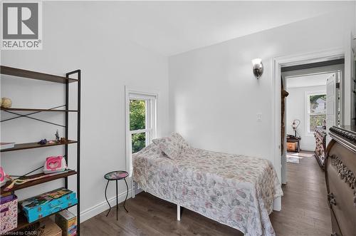 Interior room featuring wood-finish flooring, a single window with white trim, and a wall-mounted sconce - 9 Davidson Street, Cambridge, ON - Indoor Photo Showing Bedroom