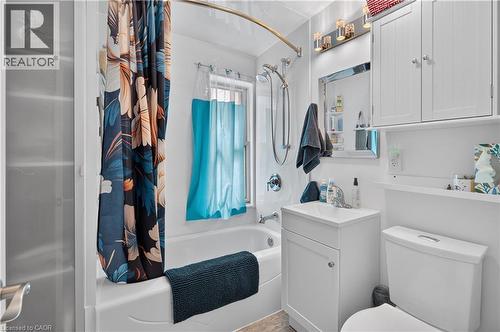 Full bathroom featuring a shower-over-tub combination with a curved shower rod, a single vanity with storage, a toilet, and overhead wall-mounted cabinetry - 9 Davidson Street, Cambridge, ON - Indoor Photo Showing Bathroom