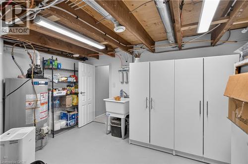 Utility space featuring exposed ceiling joists, overhead strip lighting, white built-in cabinetry, and a utility sink - 9 Davidson Street, Cambridge, ON - Indoor Photo Showing Basement