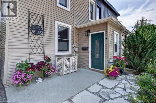 Inviting front entrance featuring a paneled door with decorative glass, an exterior wall sconce, and a stone slab pathway - 9 Davidson Street, Cambridge, ON - Outdoor