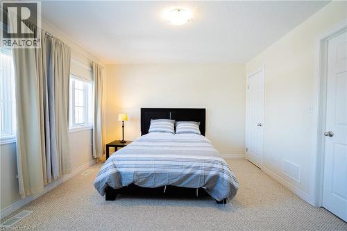 Carpeted bedroom with neutral wall tones and multiple windows providing natural illumination - 44 Medici Lane, Hamilton, ON - Indoor Photo Showing Bedroom