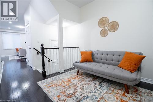 Upper-level hallway featuring dark wood-finish flooring, white walls, and a white baluster railing with a black handrail and newel post - 44 Medici Lane, Hamilton, ON - Indoor