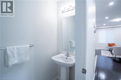 Pedestal sink with chrome faucet, wall-mounted mirror, overhead vanity lighting, and chrome towel bar - 44 Medici Lane, Hamilton, ON - Indoor Photo Showing Bathroom