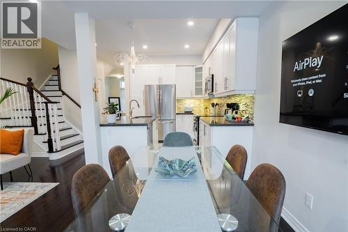 Open-concept living area featuring dark wood-finish flooring, a contemporary staircase with dark wood handrails and white risers, a modern kitchen with white cabinetry and stainless steel appliances, - 44 Medici Lane, Hamilton, ON - Indoor Photo Showing Other Room