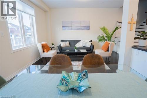 Open-concept living area featuring dark wood-finish flooring, white baseboards, and neutral wall tones - 44 Medici Lane, Hamilton, ON - Indoor