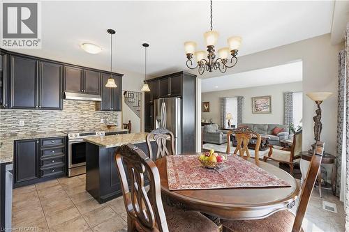 Kitchen featuring dark wood cabinetry, stainless steel appliances, a tile backsplash, and light-toned granite countertops - 1332 Baseline Road, Stoney Creek, ON - Indoor Photo Showing Dining Room