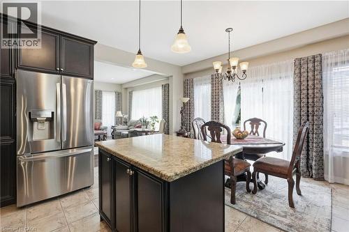 Kitchen featuring dark wood cabinetry, stainless steel French door refrigerator, central island with light-toned countertop, and tiled flooring - 1332 Baseline Road, Stoney Creek, ON - Indoor