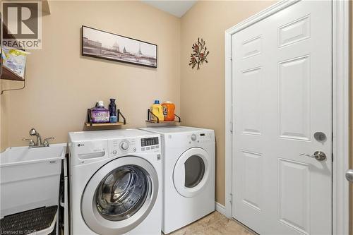 Dedicated laundry area featuring a utility sink with dual-handle faucet, full-size washer and dryer, and tiled flooring - 1332 Baseline Road, Stoney Creek, ON - Indoor Photo Showing Laundry Room