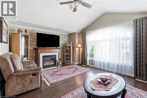 Living room featuring a prominent fireplace with a wood mantel, a textured stone accent wall, and a large arched window - 1332 Baseline Road, Stoney Creek, ON - Indoor Photo Showing Living Room With Fireplace