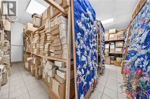 Storage room with tile flooring, fluorescent lighting, and extensive wood shelving units - 817 King Street E, Hamilton, ON 