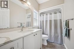 Bathroom featuring a white vanity with an integrated sink and light-colored countertop, a chrome faucet, a large wall-mounted mirror, and a shower-over-tub with a white surround - 