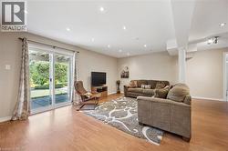 Spacious living area featuring wood-finish flooring, recessed lighting, and a sliding glass door providing exterior access - 