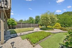 Multi-level backyard featuring gravel and artificial turf areas, a privacy fence, established trees, and a raised planter bed - 