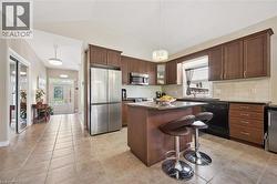 Kitchen featuring wood-finish cabinetry, stainless steel appliances, a center island with countertop seating, and tile flooring - 