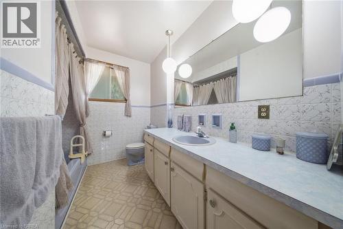 Bathroom vanity featuring a light-toned countertop, integrated sink, and wood-finish cabinetry - 1598 Highway No 6, Hamilton, ON - Indoor Photo Showing Bathroom