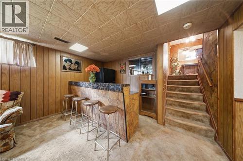 Lower-level entertainment space featuring a built-in bar with a stone-finish facade and a dark countertop, wood paneling, and a drop ceiling with integrated lighting - 1598 Highway No 6, Hamilton, ON - Indoor