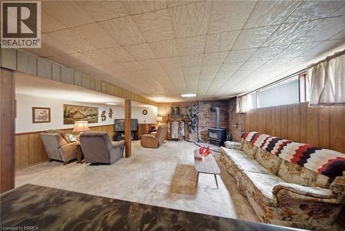 Finished lower level with carpet flooring, wood paneling, and a brick accent wall with a wood-burning stove - 1598 Highway No 6, Hamilton, ON - Indoor