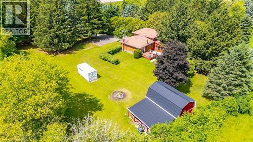 Expansive property featuring a red barn with a black roof, a residential structure with a reddish-brown roof, a large grassy area, and numerous mature trees - 1598 Highway No 6, Hamilton, ON - Outdoor