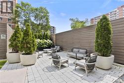 Spacious outdoor patio featuring paver stone flooring, a horizontal slat privacy fence, and mature potted arborvitae - 