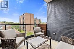 Balcony featuring a glass railing, dark brick wall, wood paneling, and a striped outdoor rug - 