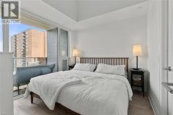 Spacious bedroom featuring wood-finish flooring and a private balcony with a glass railing - 