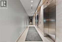 Building hallway featuring multiple brushed stainless steel elevators, recessed lighting, and a light wood-finish ceiling accent - 