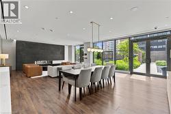 Spacious open-concept interior featuring wood-finish flooring, a contemporary linear fireplace set into a dark accent wall, and recessed ceiling lighting - 