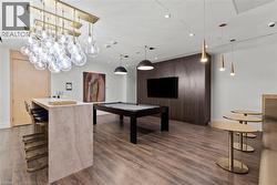Recreation room featuring wood-finish flooring, a contemporary billiard table, and a built-in entertainment center with a television - 