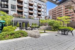 Modern paved courtyard with established landscaping, integrated seating areas, and a contemporary building facade - 