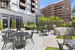 Pavered courtyard featuring multiple seating areas, built-in grills, decorative boulders, and planted greenery - 