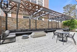 Expansive patio featuring a stone veneer privacy wall and a decorative metal pergola - 