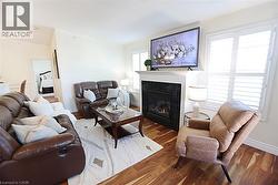 Living area featuring warm wood-finish flooring and a fireplace with a black stone surround and white mantel - 