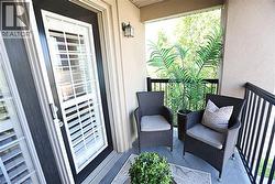 Private balcony featuring textured exterior walls, black metal railings, and a wall-mounted exterior light fixture - 