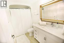 White vanity featuring a single integrated sink, stone-look countertop, and brass-tone drawer pulls - 